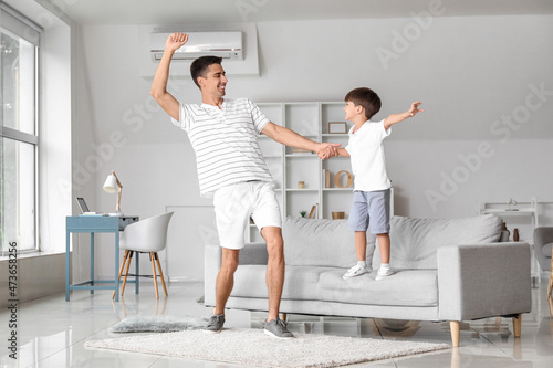 Man and his little son dancing at home