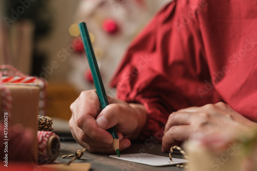 woman writing gift tag and attach to christmas present on wood table