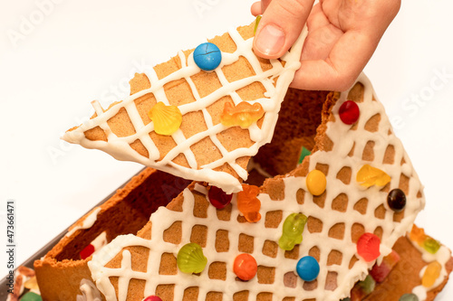 Piece of dissasembled homemade gingerbread house decorated with icing and sweets. Eating of gingerbread house after Christmas photo