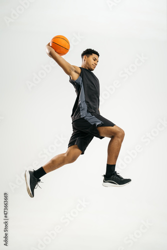 Black basketball player jumping with ball photo