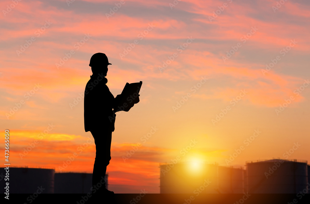 Silhouette of Engineer under inspection and checking oil storage tank, Engineer man in waistcoats and hardhats and with documents in oil storage plant