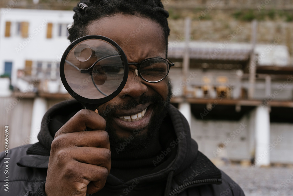 © Mattia/Stocksy - Black Man is Playing with a Magnify Glass © Mattia/Stocksy - Black Man is Playing with a Magnify Glass