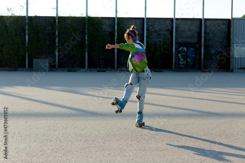 Roller-skater girl doing pirouettes in sunlight outdoor photo