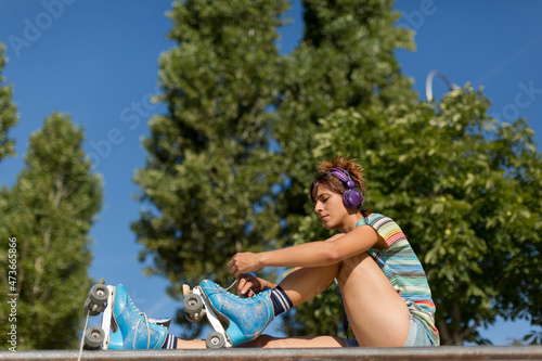 Roller-skater girl tying her skates laces outdoors photo