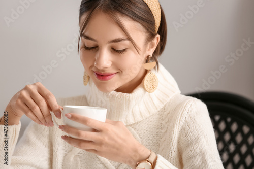 Beautiful young woman drinking tasty tea in cafe