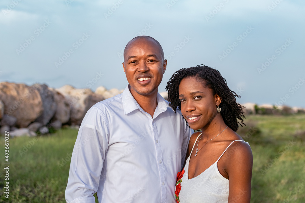 Young loving black couple standing close together outside, staring at camera smiling, grassy meadow. Happy African couple outside, Jamaica, shot on the Palisadoes strip Young loving black couple standing close together outside, staring at camera smiling, grassy meadow. Happy African couple outside, Jamaica, shot on the Palisadoes strip