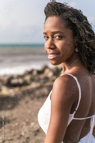 Portrait of a young attractive black woman wearing a white dress at the beach, wind blowing through hair, Jamaica, Caribbean, Black sand beach