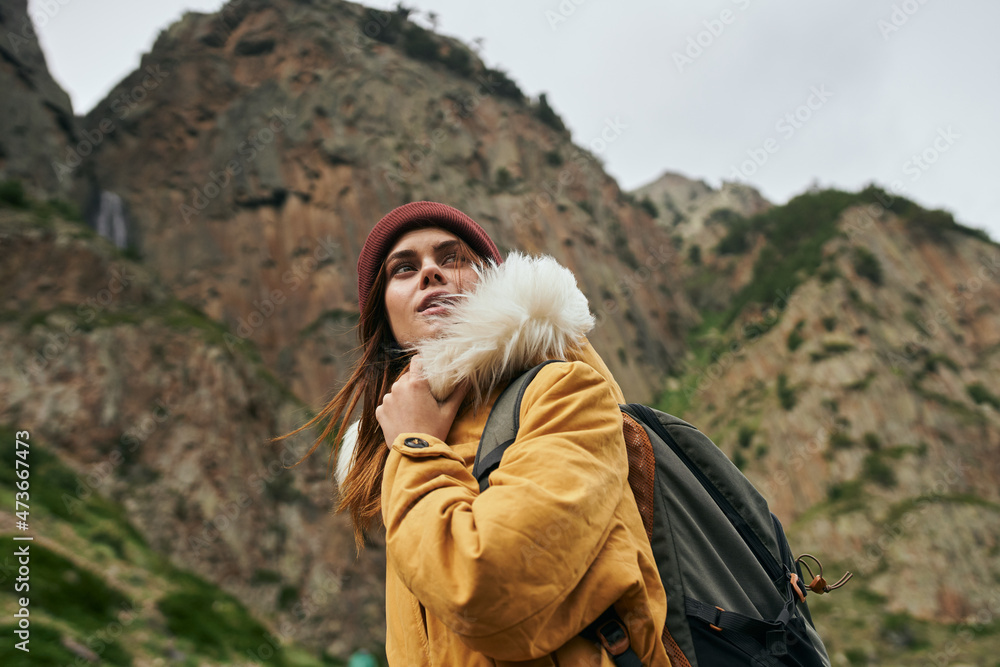 woman in a yellow jacket with a backpack in the mountains travel adventure