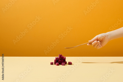Beetroot cube slice with hand hoding spoon photo