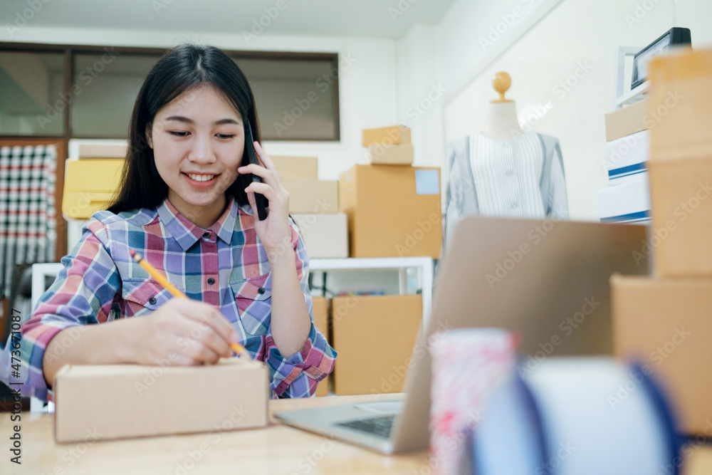 Online small business owner writing address on parcel box. Online small business owner writing address on parcel box.