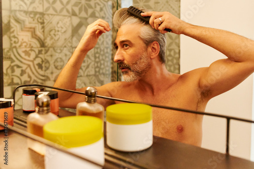 Man examining his hairline in a mirror