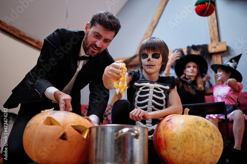 Boy and dad  putting seeds with pumpkin pulp to pot 