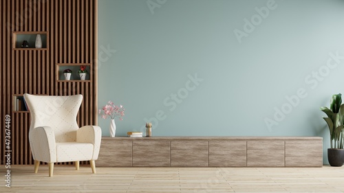 Modern living room with white armchairs on the floor, flowers and notebooks on the TV table. blue wall as background.3d rendering.