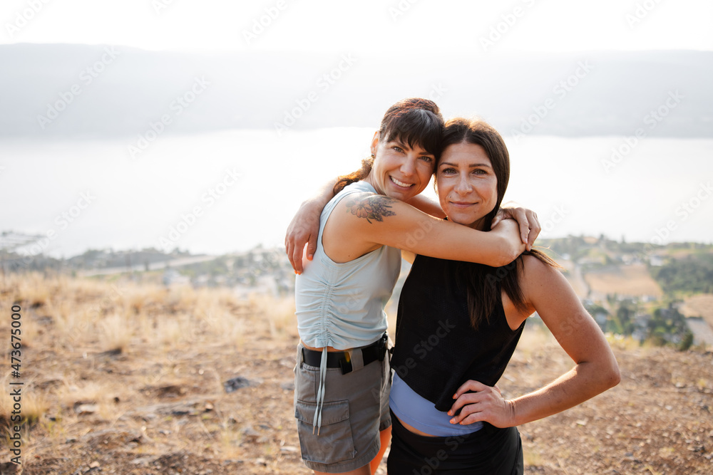 Two women smiling at the camera together outside. Two women smiling at the camera together outside.