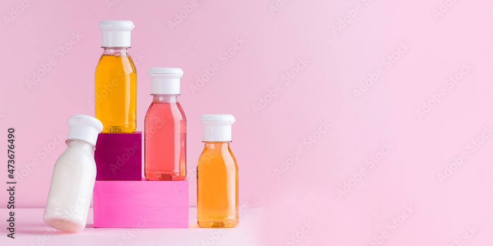 Mockup multicolored plastic bottles with shower gel, shampoo for children and adults on a pink background. Copy space. Mockup multicolored plastic bottles with shower gel, shampoo for children and adults on a pink background. Copy space.