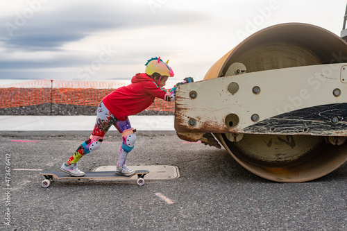 Determined skateboarder pushes on steamroller photo
