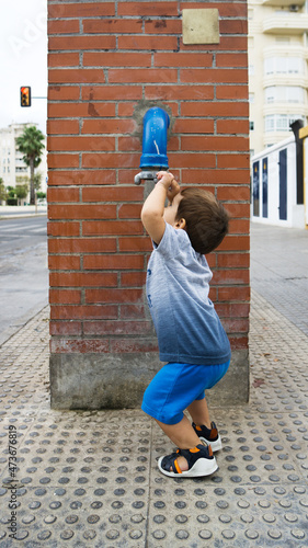 Child looking curiously at a stopcock of a water pipe