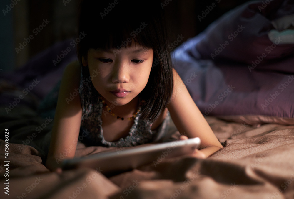 Asian little girl looking at tablet computer on the bed Asian little girl looking at tablet computer on the bed