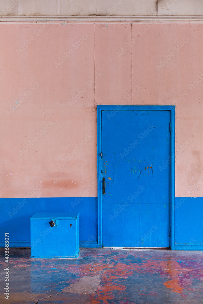 The part of an old coloured wall with blue door and box near it The part of an old coloured wall with blue door and box near it