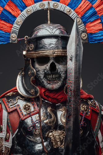 Dead roman soldier with bloody sword against gray background