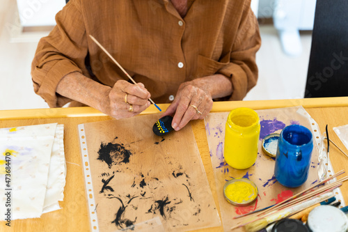 Close-up of woman painting stones with a brush photo