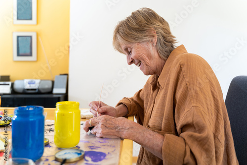 Smiley Senior woman painting mandalas on stones photo