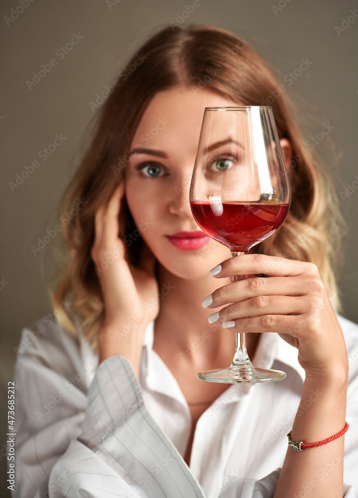 Glass of red wine in the hand of an attractive young girl Glass of red wine in the hand of an attractive young girl