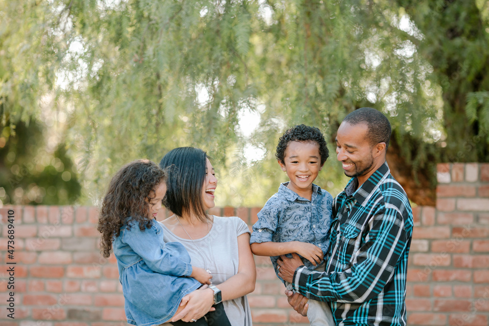 Laughing young family standing near brick wall Laughing young family standing near brick wall