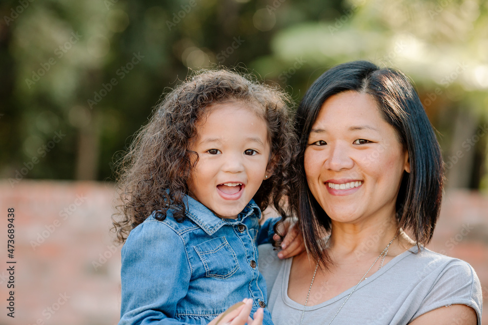 Happy Asian mom holding multiracial girl Happy Asian mom holding multiracial girl
