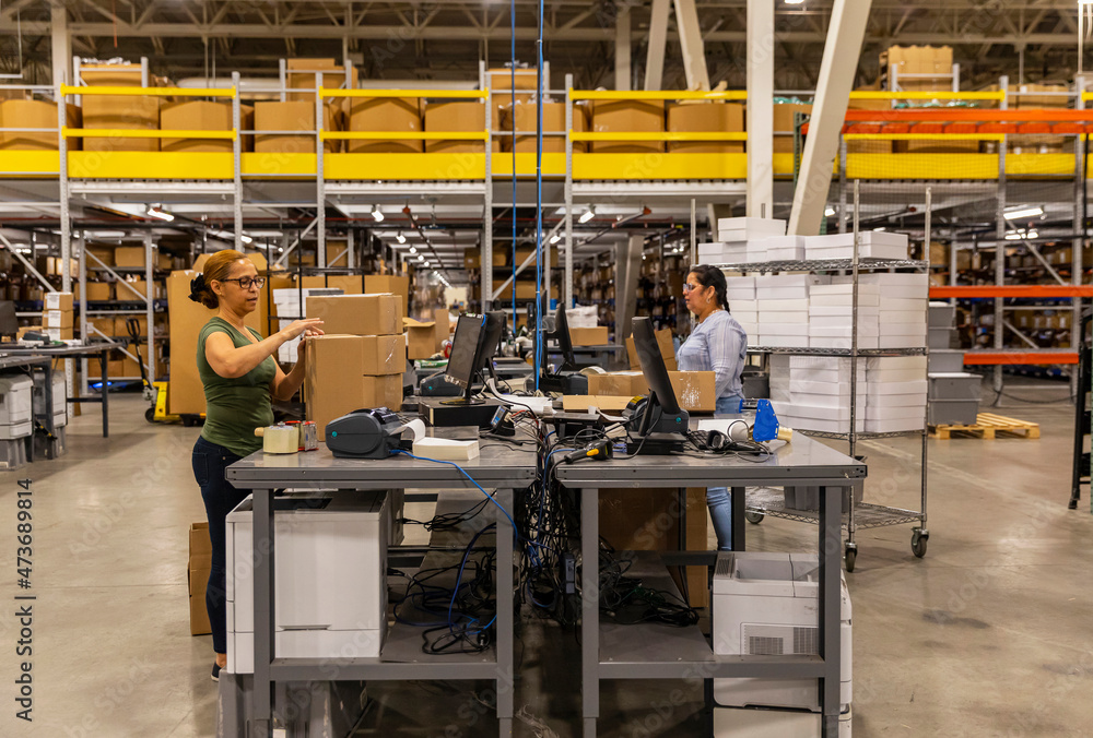 © Raymond Forbes Photography/Stocksy - Warehouse workers at shipping station at warehouse © Raymond Forbes Photography/Stocksy - Warehouse workers at shipping station at warehouse