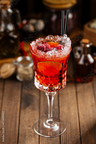 Sweet red berry alcohol cocktail in a fancy glass with ice