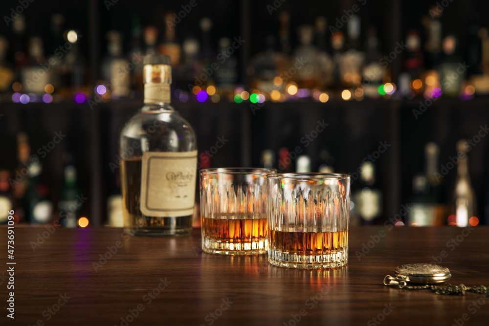 close up view of bottle of whiskey and glasses aside on color back. close up view of bottle of whiskey and glasses aside on color back.