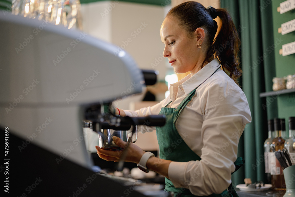 Caucasian female barista at work making coffee
