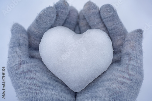 Knitted mittens with heart of snow in winter. Love concept. Valentine day background.