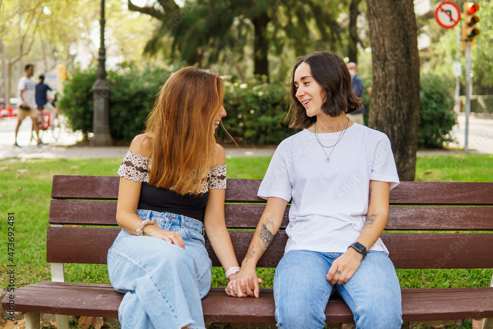 Happy lesbian couple sitting on bench Happy lesbian couple sitting on bench