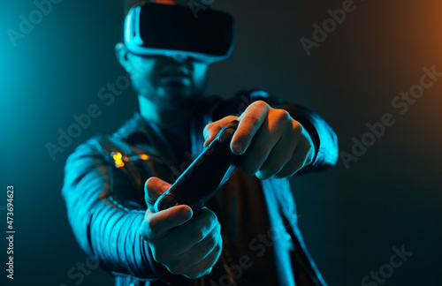 Man in VR glasses and with joystick playing videogame