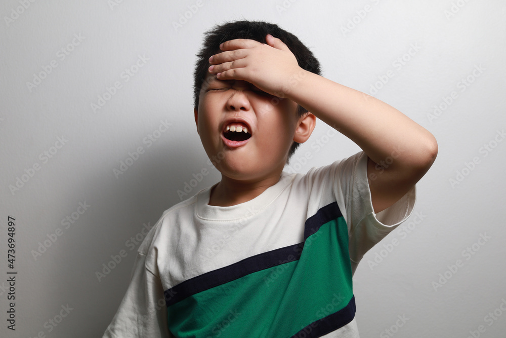 Frustrated Little Asian boy screaming with a hand holding his head isolated on grey background. Frustrated Little Asian boy screaming with a hand holding his head isolated on grey background.