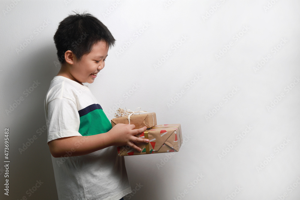 Portrait of a happy Asian boy receiving Christmas gifts, standing against a white wall. Portrait of a happy Asian boy receiving Christmas gifts, standing against a white wall.