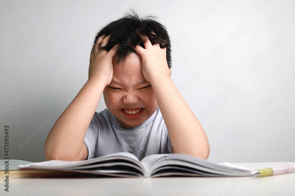 Portrait of little Asian boy bored, frustrated and fed up doing his homework