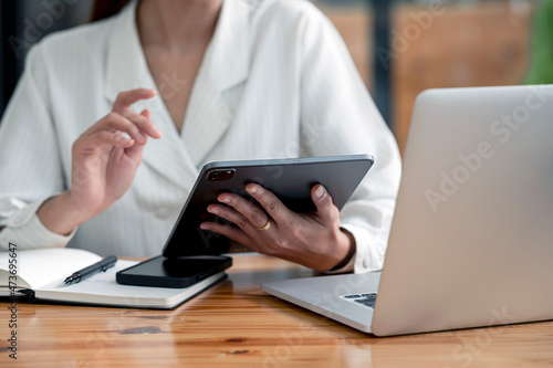 Businesswoman sitting at office and using digital tablet and laptop computer. Business strategy and planning.