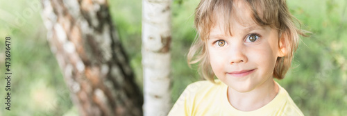 motion blur defocused photo of portrait smiling sunny kid caucasian candid boy with blonde long wavy or curly hair and sunlight on face on nature countryside forest outdoor. banner