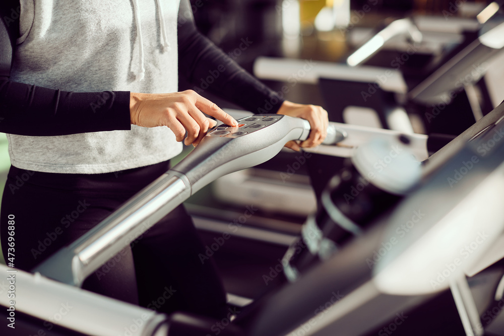 Close-up of sportswoman presses stop button after running on treadmill at gym.