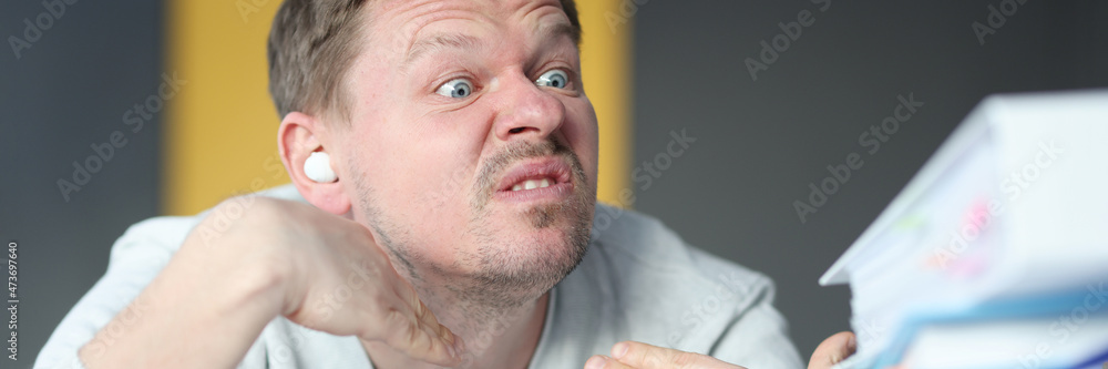 Naklejka premium Emotionally angry man looks at large pile of documents closeup