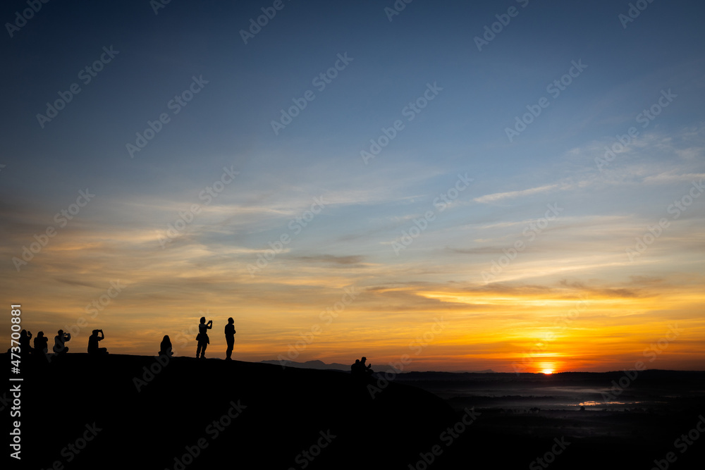 Silhouette picture of tourists taking photos with the rising sun,people watch the first light and the morning mist,sunrise in the morning at Three Whale Rocks in Phu Sing National forest,Bueng Kan