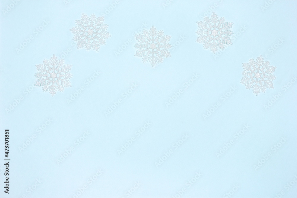 White luminous snowflake decorations on blue. Copy space. Simple winter frame background