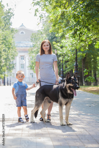 Mom and Son Walking with a German Shepherd Dog © izida1991