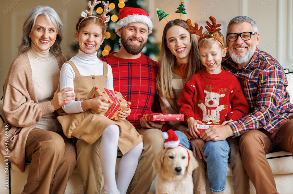 Happy beautiful large family with dog labrador retriever sitting on couch near decorated xmas tree Happy beautiful large family with dog labrador retriever sitting on couch near decorated xmas tree