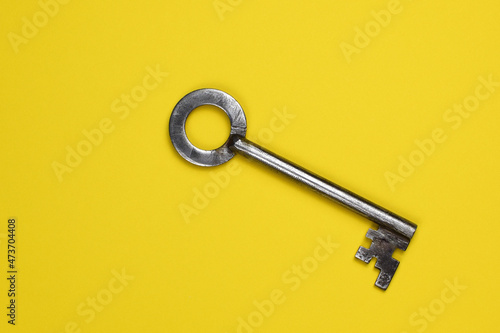 Key on a yellow background, top view. Trendy colorful photo. Trendy minimal flat lay concept.