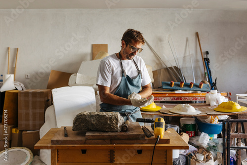 Artisan in mask working with granite stone