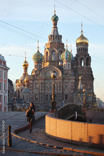 A young woman walks in front of a Russian Cathedral in Saint Petersburg.  photo